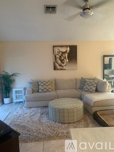 A living room with a couch, a side table, a plant, and a painting on the wall.