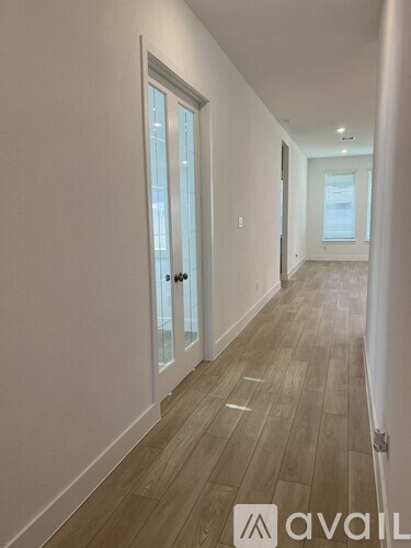 A hallway with wood flooring and white walls.