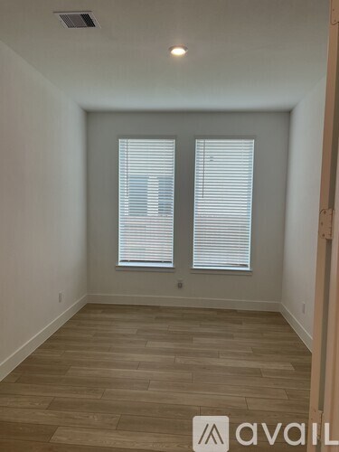 A room with wooden flooring and a window with blinds.