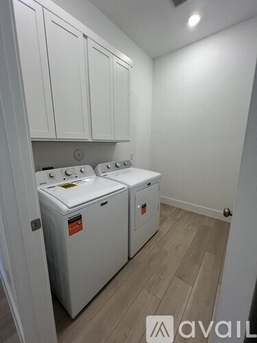 A laundry room with two washing machines and white cabinets.