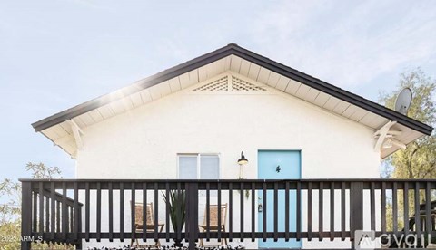A white house with a blue door and a black railing.