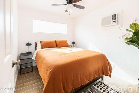 A bedroom with a bed, a ceiling fan, and a window.