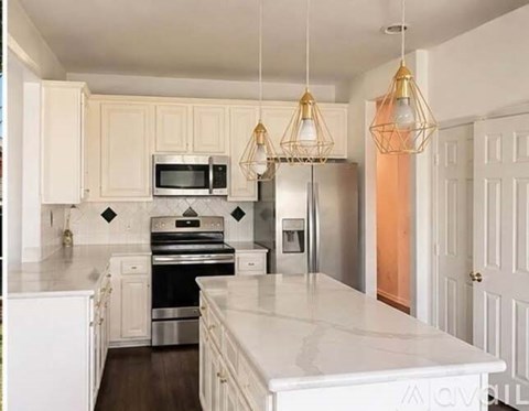 A modern kitchen with white cabinets and a white island.