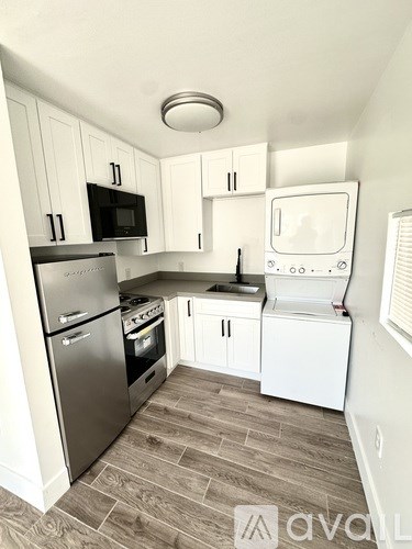 A kitchen with a stainless steel refrigerator, microwave, and white cabinets.