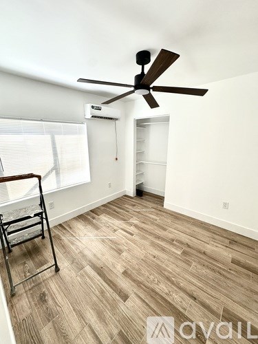 A room with a ceiling fan and wooden flooring.