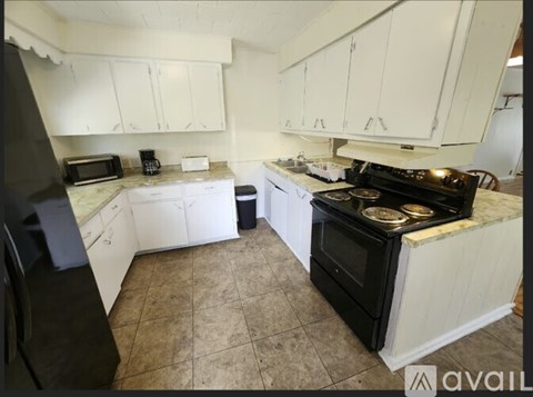 A kitchen with black appliances and white cabinets.