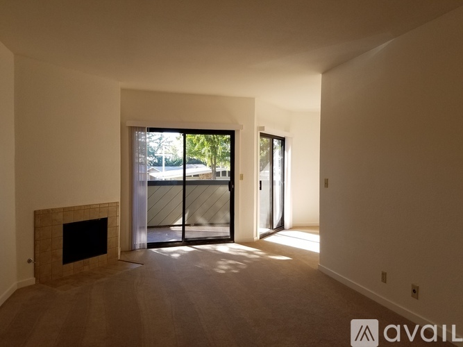 A spacious living room with a fireplace and sliding glass doors leading to a balcony.