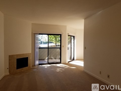A spacious living room with a fireplace and sliding glass doors leading to a balcony.
