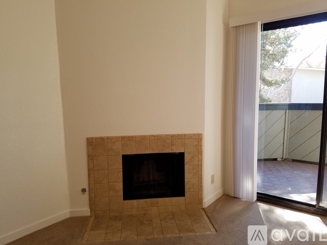A tan tiled fireplace in a room with a sliding glass door.