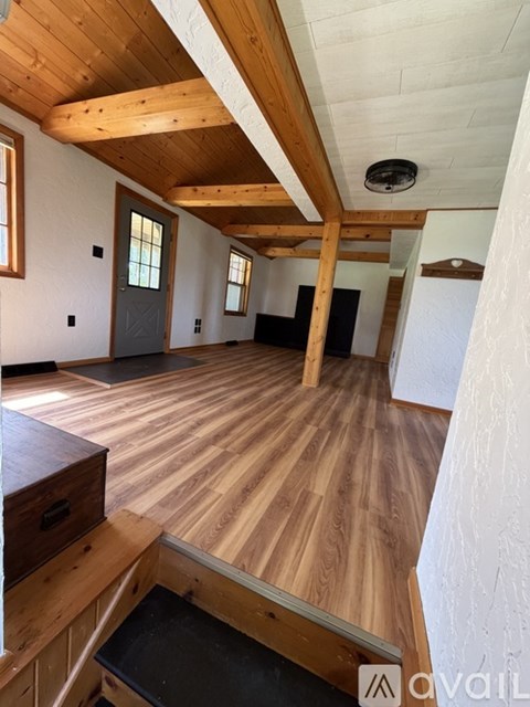 A room with wooden floors and a high ceiling with exposed beams.