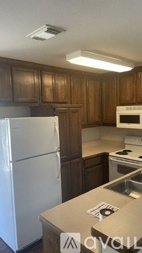 A kitchen with wooden cabinets and a white fridge.
