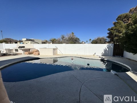 A pool with a white fence and a house in the background.
