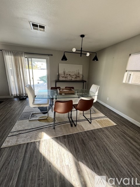 A dining room with a table set for four and a view of a pool outside.