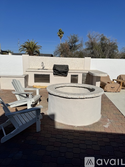 A patio with a hot tub and chairs.