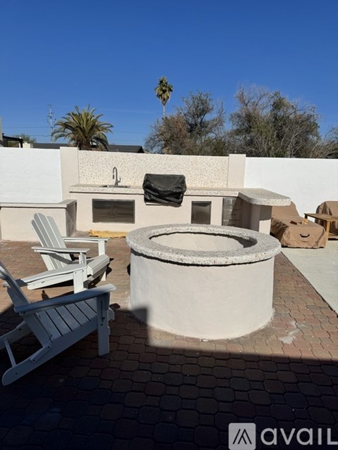 A patio with a hot tub and chairs.