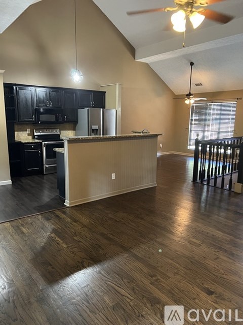 A kitchen with black cabinets and a wooden floor.