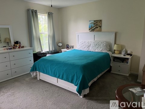 A bedroom with a white bed and a blue bedspread.