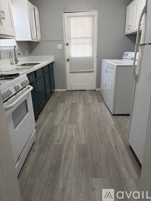 A kitchen with white appliances and wooden floors.
