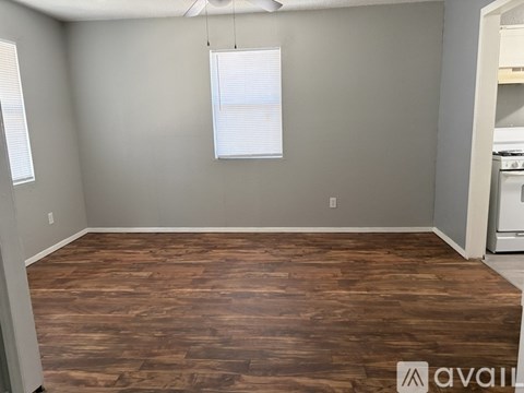 A room with wooden flooring and a window with blinds.