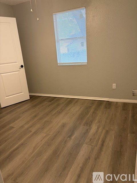 A room with a white door and wooden flooring.