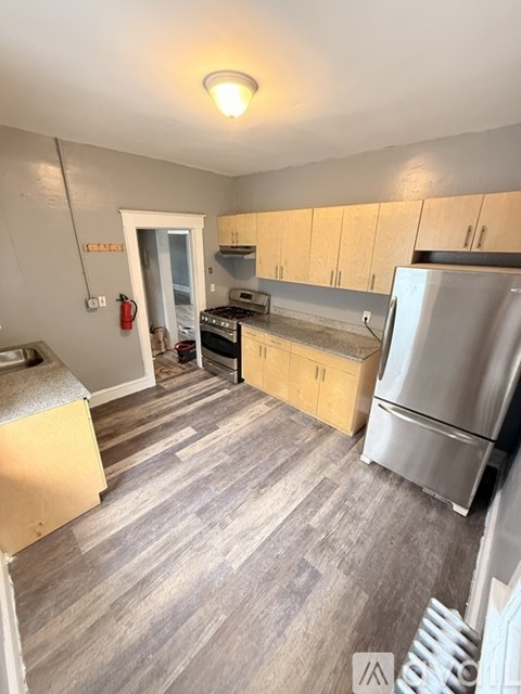 A kitchen with a stainless steel refrigerator, oven, and cabinets.