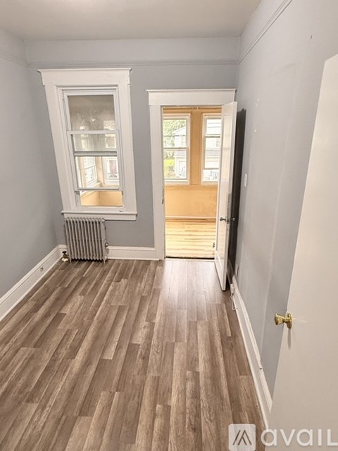 A room with wooden flooring and a door leading to another room.