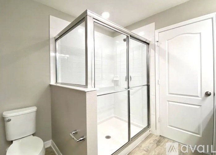 A white toilet sits next to a walk-in shower with a glass door.