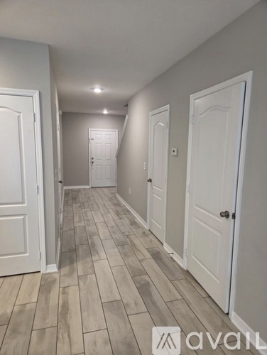 A hallway with white doors and a wooden floor.