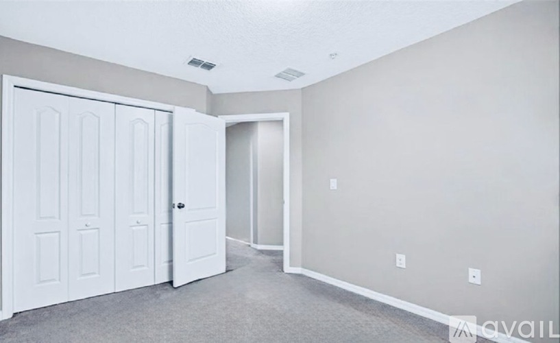 A room with a white door and a grey carpet.