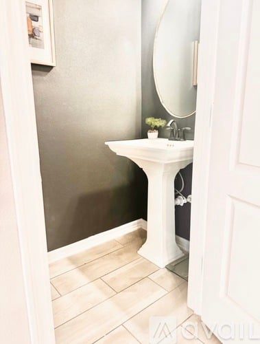 A white pedestal sink in a bathroom with a mirror above it.