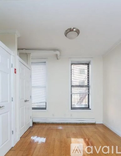 A room with a wooden floor and a window with blinds.