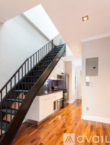 A black metal staircase with a white wall and wooden floor.