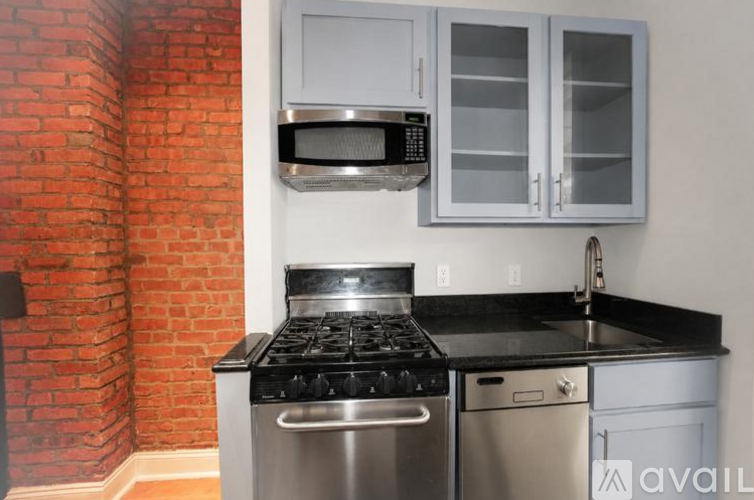 A kitchen with a brick wall and a black stove top oven.