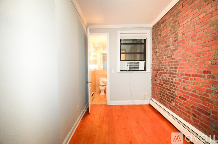 A room with a red brick wall and wooden flooring.