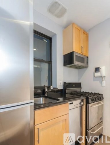 A kitchen with a stainless steel refrigerator, wooden cabinets, and a stove top oven.