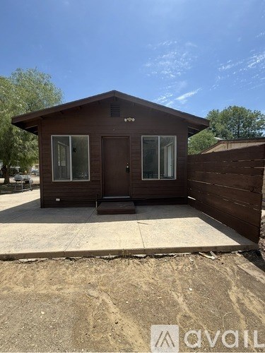 A small brown house with a brown fence in front of it.