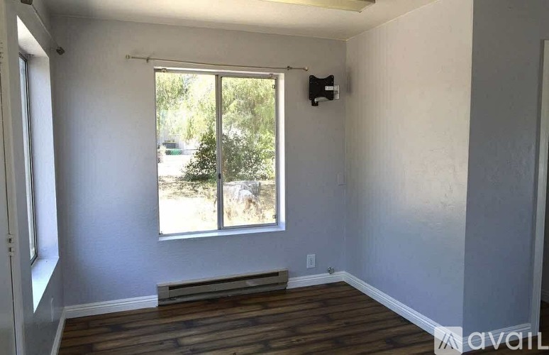 A room with a window and a flat screen TV mounted on the wall.