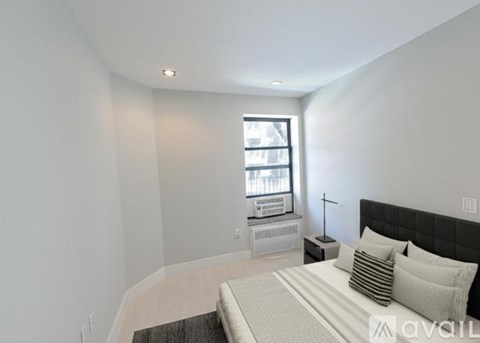 A bedroom with a bed, nightstand, and window.