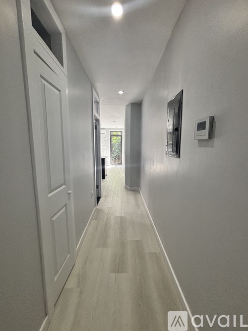 A long hallway with white walls and wood flooring.