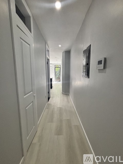 A long hallway with white walls and wood flooring.