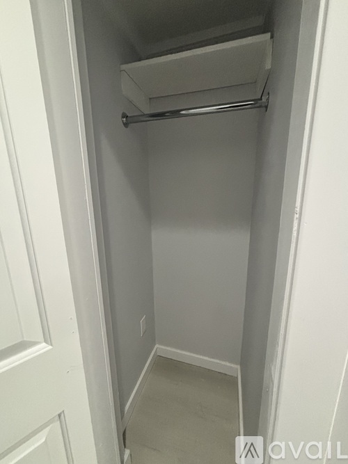 A small, empty, white closet with a shelf and a door.