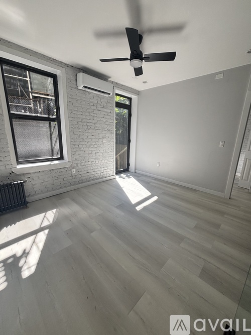A room with a ceiling fan and a window with a view of a fence and trees.