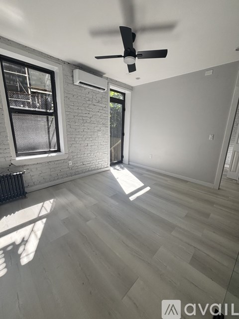 A room with a ceiling fan and a window with a view of a fence and trees.