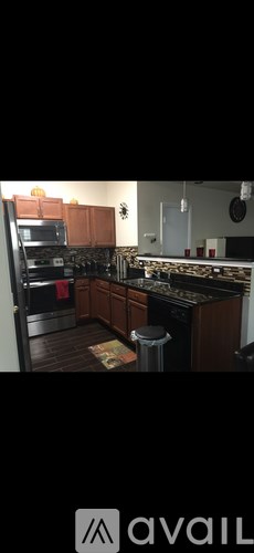 A modern kitchen with dark wood floors and stainless steel appliances.