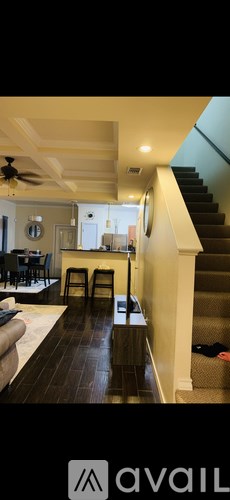 A living room with a black couch and a ceiling fan.