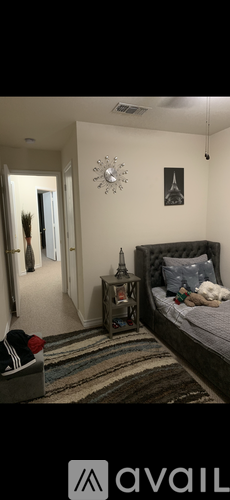 A bedroom with a bed, nightstand, and a clock on the wall.