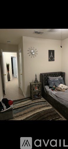 A bedroom with a bed, nightstand, and a clock on the wall.