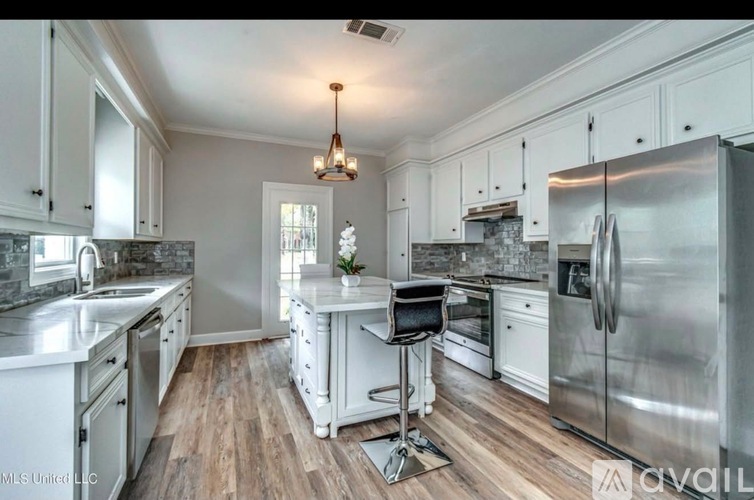 A kitchen with white cabinets and a wooden floor.