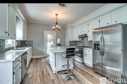 A kitchen with white cabinets and a wooden floor.