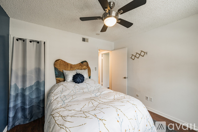 A bedroom with a bed, a ceiling fan, and a door.